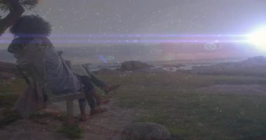 Okyanus kenarındaki bankta oturan çift, animasyon efektleriyle yıldızlı gökyüzünü izliyor. Romantik, yıldızları seyretmek, gece manzarası, sükunet, sükunet, açık hava.