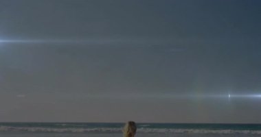 Sahilde durmuş, okyanus dalgaları üzerinde parlayan parlak ışığı izleyen biri. Gün batımı, deniz manzarası, huzur, ufuk, sükunet, yansıma