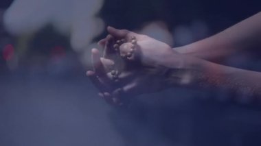 Dua boncukları, bulanık ışıkları olan eller sakin bir atmosfer yaratıyor. Meditasyon, maneviyat, tefekkür, sükunet, sükunet, huzur