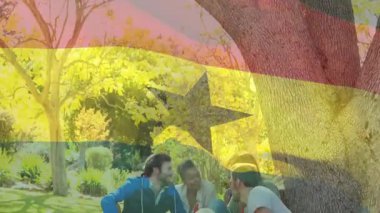 Köpekle ağacın altında oturmak, arkadaşlar Gana bayrağıyla animasyonun tadını çıkarıyor. Arkadaşlık, açık hava, doğa, rahatlama, rahatlama, çeşitlilik.