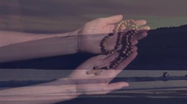 Tespih taşır, ellerini uzak figürlü sakin sahil manzarasına yaslar. Dua, maneviyat, meditasyon, okyanus, sükunet, yalnızlık.