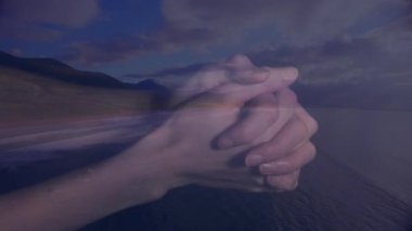 Manzaralı dağ ve okyanus manzarasının üzerinde iç içe geçmiş eller animasyon elementleriyle. Beraberlik, birlik, sükunet, doğa, uyum.