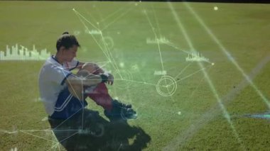 Futbolcu dijital veri işleme animasyonu ile sahada oturuyor. Spor, atlet, teknoloji, analiz, hareket takip, istatistik