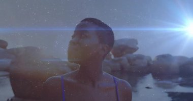 Mavi mayo giymiş, kayalık arka planda ışıltılı animasyon etkisi olan bir kadın. Moda, plaj kıyafeti, mayo, okyanus, tatil, dijital sanat