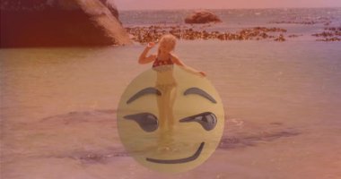 Plajda, üzerinde kocaman gülen emoji animasyonları olan mayolu bir adam. Yaz, tatil, kahkaha, okyanus, kum, eğlence