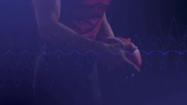 Kırmızı formalı Amerikalı futbolcu ses dalgası animasyonlu topu tutuyor. Spor, atlet, hareket, teknoloji, rekabet, güç