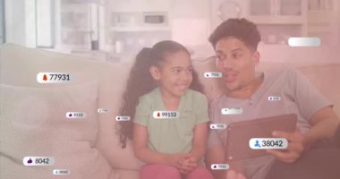 Kanepede, baba ve çocuk sosyal medya bildirimlerinin gülümsemesini izliyorlar. Aile, bağ, teknoloji, iletişim, mutluluk, ebeveynlik