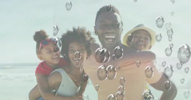 Sahilde, aile su damlacıklarının animasyonuyla gülümsüyor, eğleniyor. Tatil, deniz kenarı, aile zamanı, yaz, mutluluk, plaj tatili