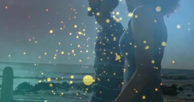 Sahilde, ışıldayan ışık parçacıkları olan siluetli bir çift animasyon etkisi yaratıyor. Günbatımı, romantizm, okyanus, rüya gibi, ışıl ışıl, mistik