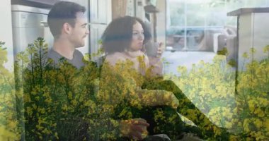 Evde kahve içen çift sarı çiçek tarlasının animasyonuna bakıyor. Rahatlama, rahatlama, sohbet, boş zaman, sanal gerçeklik, dijital etkileşim