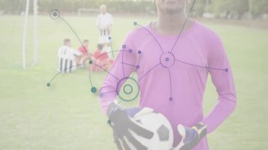 Futbol oyuncusu saha sahnesinde ağ bağlantılarıyla topu tutuyor. Spor, teknoloji, dijital, bağlantılı, yenilik, atlet