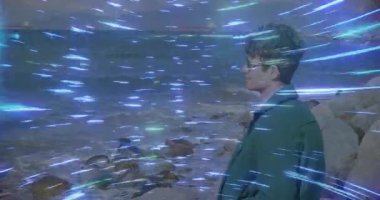 Güneş gözlüğü takan biri girdap gibi mavi ışık animasyonuyla kayalık kıyıda duruyor. Plaj, okyanus, moda, dinamik, macera, canlı