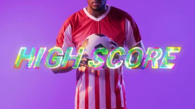 Mor zemin üzerinde yüksek puanlı metin animasyonu olan futbol oyuncusu topu tutuyor. Spor, futbol, atlet, yarışma, oyun, dijital