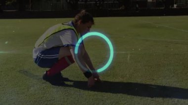 Çimlerin üzerinde parlayan çember animasyon örtüsüyle çömelmiş biri. Spor, açık hava, egzersiz, sağlık, teknoloji, dijital