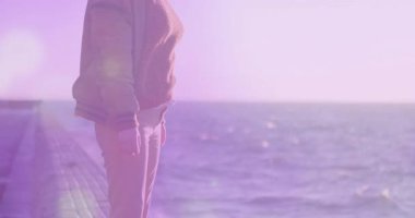 Okyanusun kenarında duran, arka planda mor ışık animasyonu olan kadın. Doğa, su, dalgalar, kadın, yaratıcılık, aydınlatma