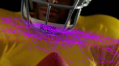 Pembe parçacıkları olan, kaskın etrafında dönen, sarı formalı bir futbolcu. Spor, atlet, hareket, dinamik, enerji, canlı