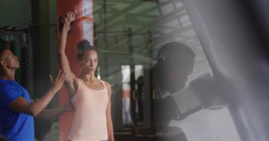 Spor salonunda, spor eğitmeni animasyon kullanarak bir kadına egzersiz rutininde rehberlik ediyor. kişisel antrenör, antrenman, koçluk, teknoloji, sağlık, eğitim
