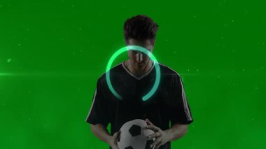 Futbol oyuncusu yeşil arka planda parlayan dairesel animasyonu olan topu tutuyor. Spor, futbol, atlet, rekabet, dijital, fütüristik