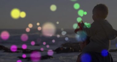 Sahilde, renkli animasyonlarla dolu bir çocuk yetişkinlerin omuzlarında oturuyor. Tatil, deniz kenarı, ebeveynlik, bağlanma, yaz, okyanus