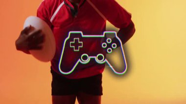 Rugby topu, turuncu arka planda oyun kontrolörü animasyonu olan biri. oyun, spor, yarışma, eğlence, teknoloji, joystick