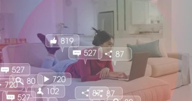 Evde dizüstü bilgisayar kullanan bir kadın ve sosyal medya bildirimleri animasyonu örtüyor. Teknoloji, iletişim, dijital, internet, ağ, yaşam tarzı