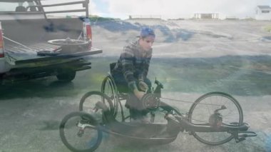 El bisikleti monte ediliyor, tekerlekli sandalyedeki adam sahil yolunda park halindeki kamyonun yanında. Uyarlanabilir spor, hareketlilik, bağımsızlık, bisiklet, açık hava, araç