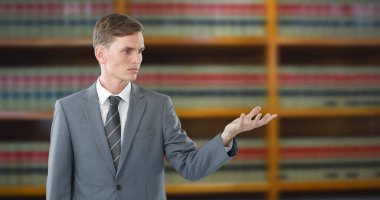 Takım elbiseli genç bir avukat hukuk kitaplarının önünde kendinden emin bir şekilde savunmasını sunuyor. Avukat, mahkeme, dava, hukuk, adalet, profesyonel