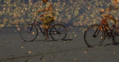 İnsanlar plajda parlak ışık animasyonlarıyla bisiklete biniyorlar. Bisiklet, deniz kenarı, gün batımı, boş zaman, tatil, ışıltı