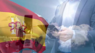 Parlak gökyüzü arkaplanlı akıllı telefon kullanan birinin üzerinde İspanyol bayrağı sallıyor. Vatanseverlik, teknoloji, iletişim, kutlama, telekomünikasyon, mobil