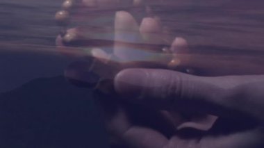 Gün batımında huzurlu manzaranın üzerinde dua boncukları tutmak, eller animasyon etkisi yaratır. Maneviyat, meditasyon, sükunet, dinginlik, farkındalık.