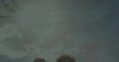 Yıldızlı gece gökyüzünün altında, siluetli çift birlikte oturup animasyon izliyorlar. Romantizm, yıldızları seyretme, boş zaman, açık hava.