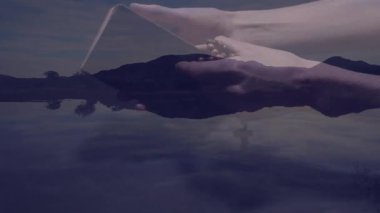 Huzurlu göl üzerinde açık kitap ve boncuklar tutan kişi doğa animasyonunu takdir ediyor. Farkındalık, sükunet, manzara, yansıma, meditasyon, açık hava