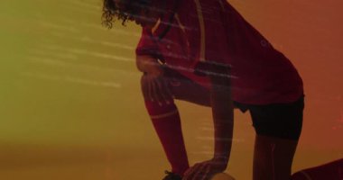 Kırmızı spor üniforması içinde, canlı turuncu ve sarı arka plana karşı duran biri. Sporcu kıyafeti, aktif, enerji, dinamik, renkli.