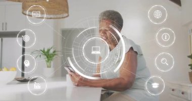 Dijital arayüzlü akıllı telefon, mutfak ortamındaki yaşlı kadın. Teknoloji, son sınıf, mobil, dokunmatik ekran, yaşam tarzı, yenilik