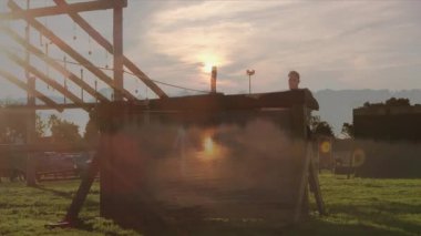 Engelli parkurun üzerinden atlayan kişi, gölün kenarında gün batımına karşı siluet oluşturmuş. Macera, meydan okuma, aktif, kararlılık, fitness, açık hava