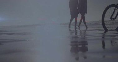 Sahilde bisikletlerin yanında yürürken, insanlar lens ışığı efektiyle siluete büründüler. Günbatımı, sahil şeridi, boş zaman, yaz, tatil, seyahat