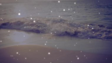 Dalgalar yavaşça kumlu sahile çarpıyor. Suyun üzerinde ışıl ışıl ışık animasyonu var. Okyanus, deniz manzarası, kıyı şeridi, tatil, dinlenme, sükunet