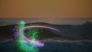 Renkli ışık yollarının animasyonu gün batımında okyanus dalgaları üzerinde desenler oluşturuyor. Siluet, huzur
