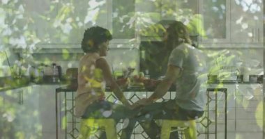 Masada oturan iki kişi, yapraklı bitkiler ve animasyon sahnesi. İşbirliği, takım çalışması, yaratıcılık, beyin fırtınası, tasarım, çalışma alanı