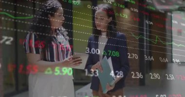 İki kadın ofis ortamında borsa veri animasyonunu tartışıyor. İş, finans, tartışma, analiz, takım çalışması, kurumsal