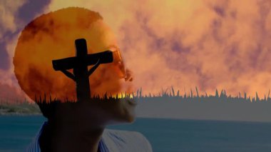 Arka planda canlı gün batımı gökyüzü ile haçın önünde gülümseyen kişi. ruhani, siluet, tefekkür, huzur, huzur, sükunet