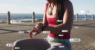 Kumsalda koşan, sosyal medya animasyon uyarılarıyla akıllı bakışları kontrol eden bir kadın. Fitness, egzersiz, teknoloji, dijital, aktivite, yaşam tarzı