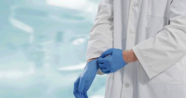 Beyaz arka plana cerrahi eldiven takan erkek doktorun orta bölümü. Tıbbi yeniden ölçüm ve covid 19 salgın konsepti