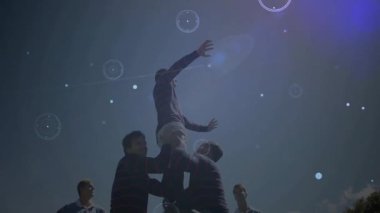 Rugby oyuncuları dijital veri işleme animasyonu eşliğinde takım arkadaşını kaldırıyorlar. Takım çalışması, spor, dinamik, dijital örtüşme, hareket, atletik