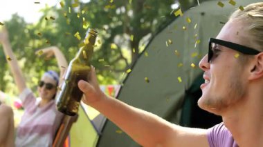 Güneş gözlüğü takmış, konfeti düşüşünün animasyonuyla şişeden su içen biri. İçecek, hidrasyon, kutlama, eğlence, şenlik, parti
