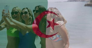 Cezayir bayrağı animasyonuyla selfie çeken, plajda mayo giyen kadınlar. Tatil, yaz, deniz kenarı, vatanseverlik, poz, arkadaşlık