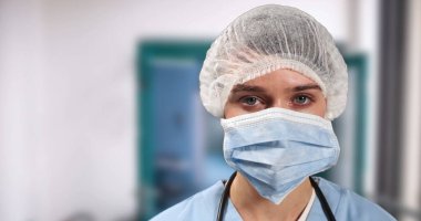 Hastanede yüz maskesi takan beyaz kadın cerrahın portresi. Coronavirus covid 19 salgını sırasında hastanede hijyen ve enfeksiyon önleme.