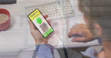 Ekranda QR kodlu akıllı telefonu tutan adam pasta dükkanında gülümseyen kadın fırıncıyla karşı karşıya. covid-19 aşı sertifikası ve sağlık kartı konsepti