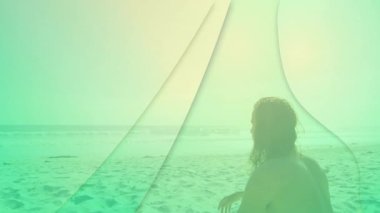 Kumsalda oturan, soyut yeşil animasyon şekilleriyle çevrili biri. yaratıcılık, dijital sanat, rahatlama, kıyı, tatil