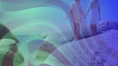 İki çocuk renkli dalga animasyonlarıyla kayaların üzerinde el ele tutuşuyor. Çocuklar, arkadaşlık, macera, açık hava, kaynaşma, birlik